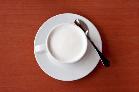 White milk in cup on brown wooden