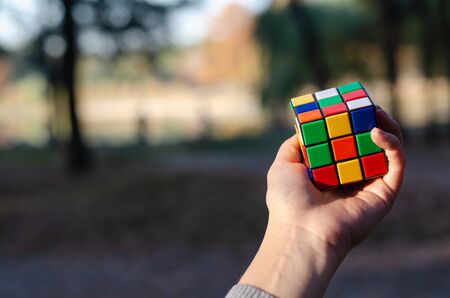 Kyiv, Ukraine - October 18, 2019. Rubiks cube in a female hand against the background of nature in the rays of the setting sun.のeditorial素材