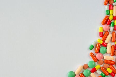 Heap of multi-colored pills, tablets and capsules on a white background. Top view. Close up of medicines. Copy spaceの写真素材