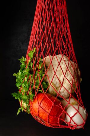 Eco friendly reusable mesh string bag with various fresh organic vegetables on black background. Alternative to plastic bags. Zero waste shopping concept. Close-upの写真素材