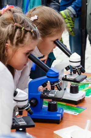 Kyiv, Ukraine - September 28, 2019. Shevchenko park. Science Picnics. Two curious little girls look through microscopes. The concept of popularization of science.のeditorial素材