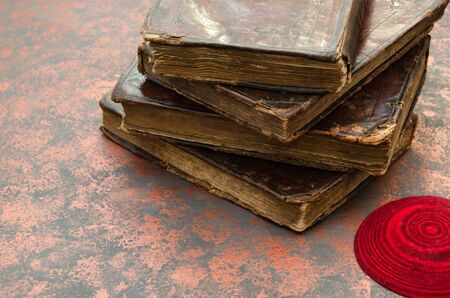 A stack of old leather-bound Jewish books with gold stamping and red knitted jewish bale. Closeupの写真素材