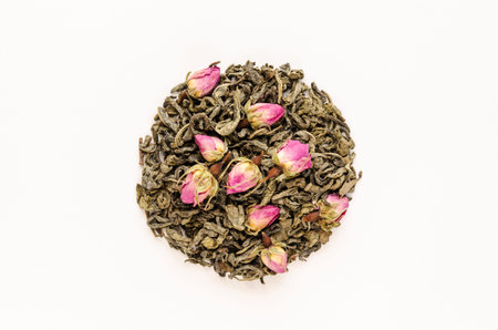 Dried green tea leaves with rosebuds on white background. Healthy natural drinks concept. Closeup. Top viewの写真素材