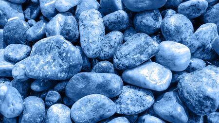 Wet sea pebbles toned in classic blue color. Abstract natural trendy background. Zen and calm concept. Close-up. Selective focusの写真素材