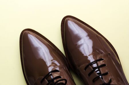 Close-up of stylish brown female patent leather shoes on pastel light yellow background. Fashion blog, magazine, beauty concept. Minimal composition. Flat lay. Top viewの写真素材