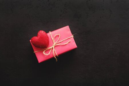 Pink gift box and red heart on black background. Gift for Valentine's Day, birthday or mother's day. Top view, copy spaceの写真素材