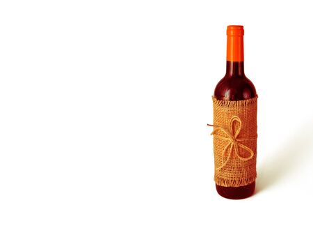 Bottle of red wine wrapped in burlap tied with twine on white background. Holidays concept. Ideas of DIY gift wrapping. Closeup. Copy spaceの写真素材