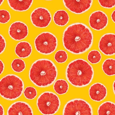 Seamless pattern of grapefruit in cross section. Top view of pink juicy grapefruit halves on yellow background. Mockup for fabric print, wrapping paper, wallpaperの写真素材