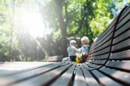 Unrecognizable mom and little son sitting on bench in city park. Spending time together with children in the summer outdoors. Copy spaceの写真素材