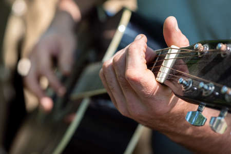 Man playing classical guitar sitting near tent outdoors. Closeup of hands. Selective focus. Summer vacation and traveling conceptの写真素材