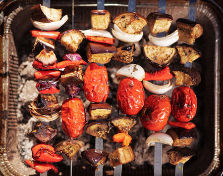 Cooking vegetables on grill outdoors. Grilled veggie skewers. Barbecue and picnic season concept. Top viewの写真素材