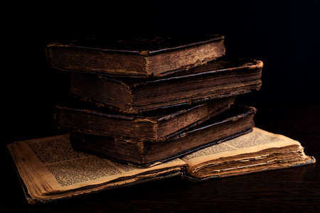 Stack of old worn shabby jewish books in leather binding on the open pages of Machzor in the dark. Closeup. Selective focus. Low keyの写真素材