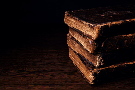 Stack of old worn shabby Jewish books in leather binding in the dark. Closeup. Selective focus. Copy spaceの写真素材