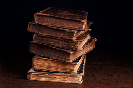 Stack of old worn shabby books in leather binding on dark background. Closeup. Selective focusの写真素材