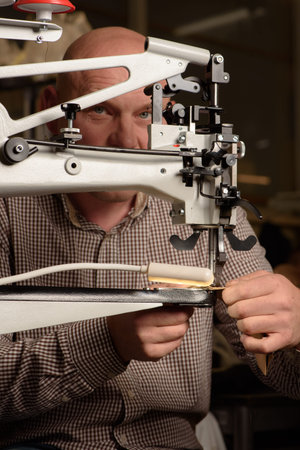 Industrial sewing machine in workshop of shoemaker. Bootmaker setting up professional sewing...