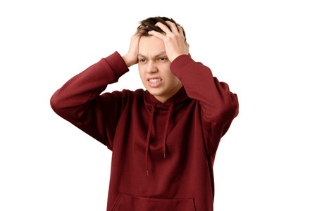Shocked teenager feeling despair holding his head in his hands, isolated on white background. Angry...
