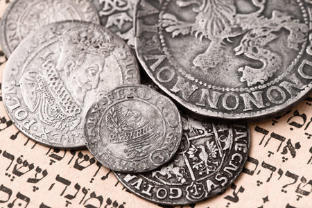 Pile of old silver coins on open Siddur page. selective focus. close upの写真素材
