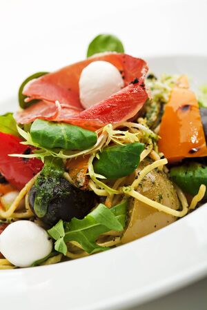 Spaghetti with Vegetables, Ham, Black Olives, Rucola and Pesto Sauceの写真素材