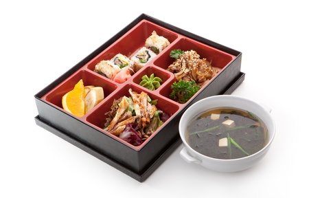 Japanese Meal in a Box (Bento) - Salad, Meat Cuts and Sushi Roll, Orange and Banana. Garnished with Miso Soupの写真素材