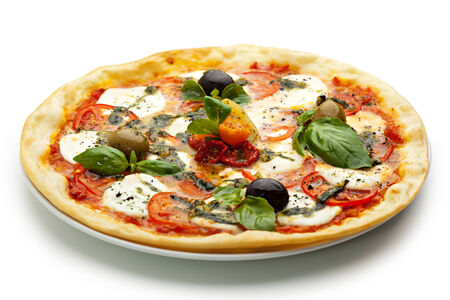 Pizza with Mozzarella Cheese and Fresh Tomato and Pesto Sauce. Garnished with Dried Tomato, Green and Black Olives and Basil Leavesの写真素材