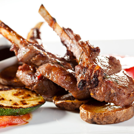 Roasted Lamb Chops on Potato with Tomato and Zucchini Garnished with Sauceの写真素材