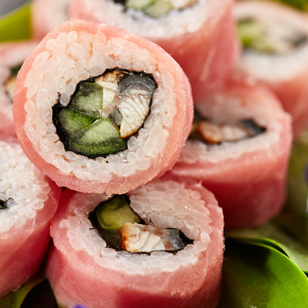 Tuna Maki Sushi - Roll made of Smoked Eel and Cucumber inside. Fresh Raw Tuna outside. Japanese Cuisine and Natural Flower Conceptの写真素材