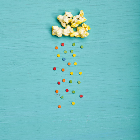 Weather Concept - Top View of Creative Popcorn Clouds with Colorful Sweet Rain on Blue Background. Minimal Concept. Flat Layの写真素材
