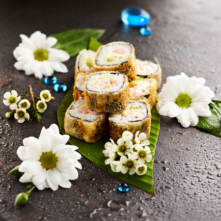 Tempura Maki Sushi - Deep Fried Sushi Roll made of Shrimps, Avocado and Cream Cheese inside. Sushi Roll Served on Banana Leaf. Japanese Sushi Food and Natural Flower Concept.の写真素材