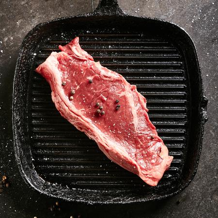 Raw Striploin Steak on Cast Iron Frying Panの写真素材