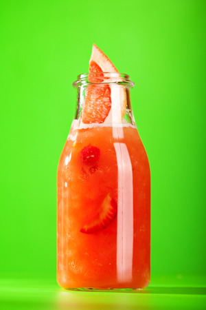 Summer Lemonade Cocktail - Grapefruit and Strawberry Lemonade. Lemonade Glass Bottle on Bright Green Background.の写真素材