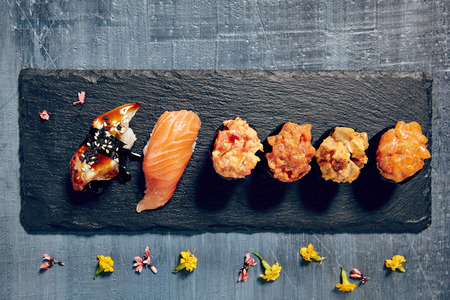 Beautifully served sets of sushi nigiri and gunkan with fish, rice and vegetableson dark copyspace background.の写真素材