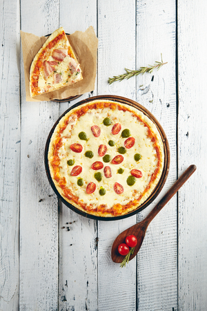 Pizza margarita with mozzarella cheese cherry tomatoes and pesto sauce on round wooden boardの写真素材