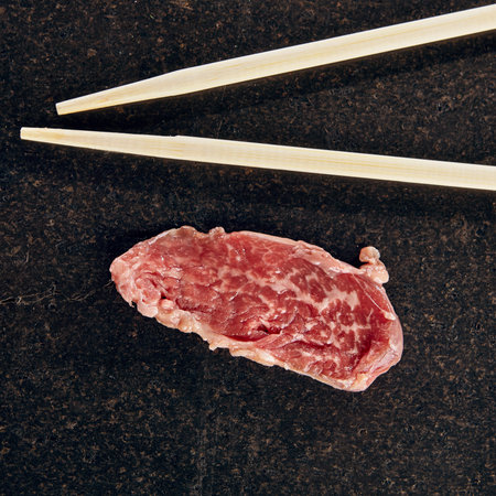 Meat slice on black stone with chopstick. Top Viewの写真素材