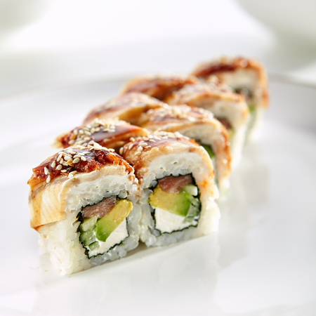 Kanada sushi rolls with salmon, eel, Philadelphia cheese, avocado and cucumber served on white flat plate. Asian menu for gourmets in luxury restaurantの写真素材