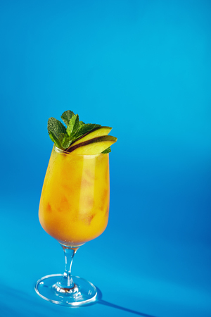 Smoothie with Orange and Pear. Dressed with Pear and Mint. Drink on Blue Backgroundの写真素材