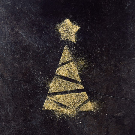 Merry Christmas and Happy New Year greeting card with gold minimal christmas tree made of glitter sand on black slate backgroundの写真素材