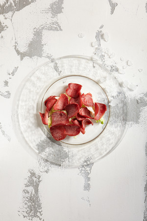 Thin slices of deli meats veal venison on transparent flat plate on white rustic copyspace background. Top Viewの写真素材