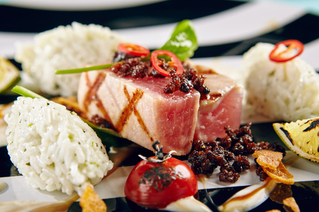 Menu of gastronomic restaurant. Tuna and coconut rice with herbs seasonings and lime slices served on black and white plateの写真素材