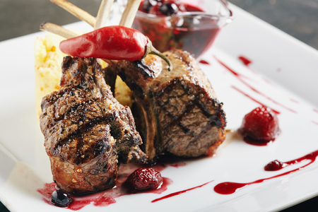 Grilled Restaurant Food - Rack of Lamb Barbecue with Garnish, Berry Sauce  on Black Stone Backgroundの写真素材