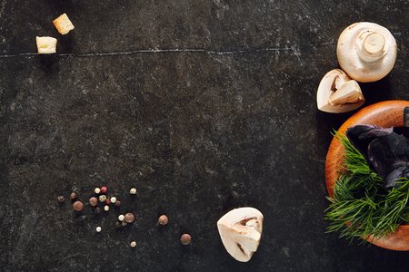 White Champignon Mushrooms on Dark Stone Plate Background with Dill, Basil, Pepper and Croutons Top View. Whole and Sliced Mushroom with Herbs for Recipe Templateの写真素材