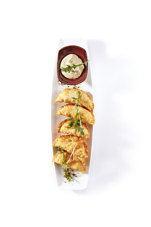 Hot Appetizers with Mini Chebureki, Cheese and Greens Isolated on White Background. Restaurant Starter Menu with Crispy Burnt Turnovers, Pies or Samosa with Spicy Sause and Arugula Close Upの写真素材