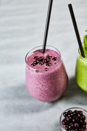 Close-up picture of glass of smoothy with juicy bilberry banana and tasty yogurt. Purple cooling beverage. Summer drink concept. Isolated on grey backgroundの写真素材