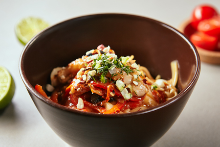 Close-up portrait of chinese noodles with chicken and sauce on coconut milk. Asian style food concept. Colourful savory lunch looking appetizing on grey tableの写真素材