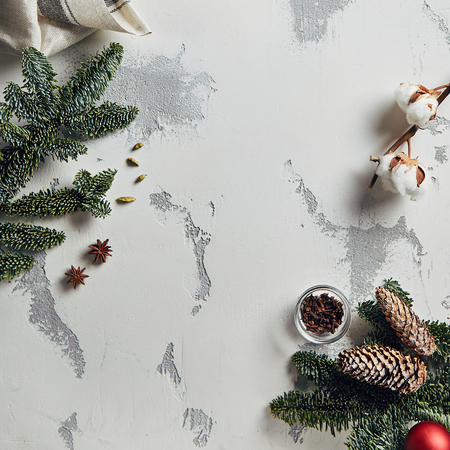 Vintage New Year Background with Spruce Branches, Traditional Winter Spices, Herbs and Natural Cotton Branch on Gray Plaster Texture Top View. Retro Christmas Table with Place for Text or Copyspaceの写真素材