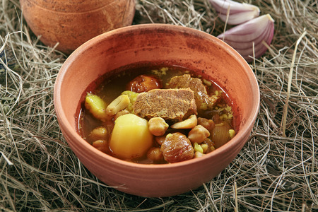 Homemade Lamb Soup Piti or Putuk with Cherry Plums in Vintage Ceramic Bowl on Rustic Background. Azerbaijani Bozbash with Mutton, Vegetables and Spices or Clear Sturdy Seasoned Broth Close Upの写真素材