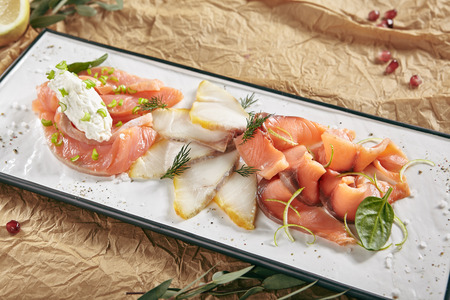Exquisite Serving Restaurant Plate of Smoked Salted Raw White Fish Fillet with Red Fish Sashimi. Delicacy Fresh Seafood Dish with Toothfish, Salmon and Tuna Meat on Rustic Background Close Upの写真素材