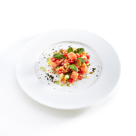 Restaurant Starter Menu with Raw Salted Salmon Slices, Tomato and Cucumber Isolated on White Background. Diced Red Fish or Trout with Vegetables, Herbs and Spices on Elegant Flat Plate Close Upの写真素材