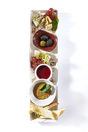 Wine Plate with Camambert, Mozzarella, Chicken Pate, Sweet Jam, Grapes, Nuts and Olive. Various Fruit, Meat and Cheese Snacks with Croutons Isolated on White Backgroundの写真素材