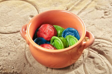 Creative Serving Kids Food with Colored Dumplings, Ravioli or Pelmeni in Natural Ceramic Pot Close Up. Macro Photo of Blue, Green and Red Tortellini for Children Main Menuの写真素材