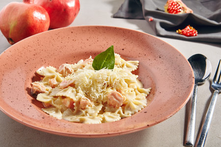 Farfalle pasta al dente with salmon in cream sauce on rustic plate. Traditional italian seafood macaroni with trout, parmigiano reggiano cheese, spices and greens in restaurant plateの写真素材
